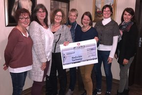 Es sind 6 Frauen abgebildet, die sich über den Scheck freuen.