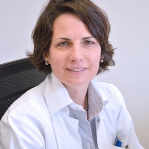 Zu sehen ist Frau Hoffmann, sie hat eine Kurzhaarfrisur und braune, etwas wellige Haare.