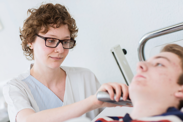 Eine Pflegerin misst einem Jugendlichen Fieber.