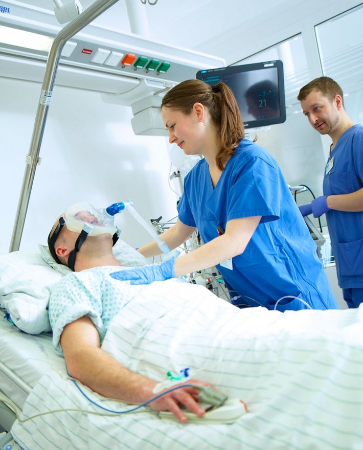 Zwei Pflegekräfte kümmern sich auf der Intensivstation um einen Patienten.