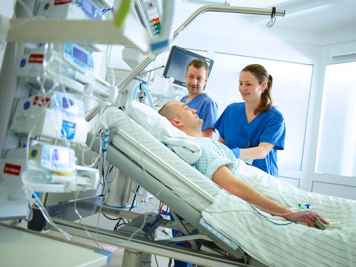 Zwei Pflegekräfte kümmern sich auf der Intensivstation um einen Patienten.