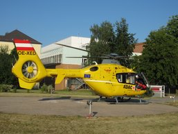 Auf dem Bild sieht man einen gelben Not-Hubschrauber auf der Wiese.