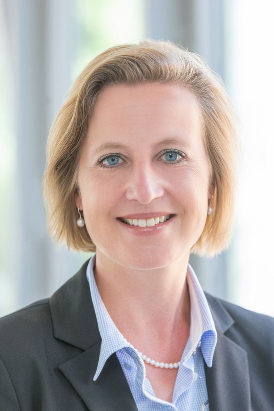 Auf dem Bild sehen Sie Frau Stierstorfer. Sie trägt eine blonden Bob, eine Perlenkette und ein hellbkaues Hemd mit Blazer