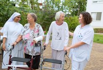 Spaziergang im Patientengarten (Foto: Paul Mazurek) Die Pflegekräfte unterstützen zwei Patientinnen bei einem Spaziergang im Patientengarten.