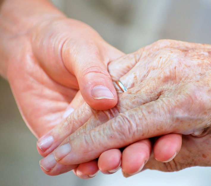 Eine junge Hand hält eine ältere Hand fest. 