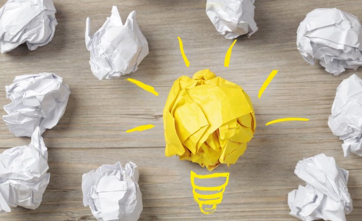 Eine Birne und Papierbälle stehen für "Idee, Konzept"