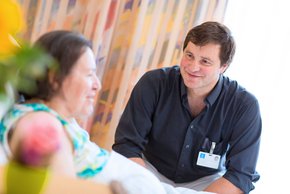 Dr. Roland Braun, leitender Arzt der Klinik für Palliativmeidzin, ist mit einer Patientin im Gespräch vertieft.